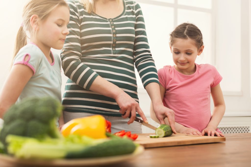 Woman with daughters cooking salad Discover the magnificent truth about yourself.